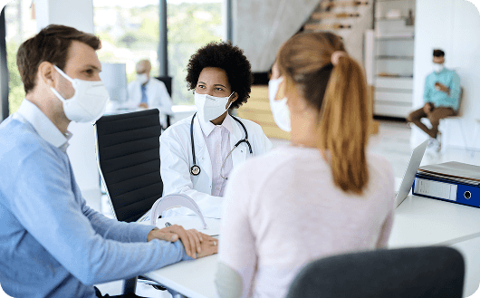 Medops Enfermedades raras 4 smiling black doctor with face mask talking couple medical counselling clinic 1